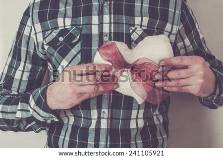 Man in plaid shirt holding a fabric heart with a red ribbon. Valentine\'s day