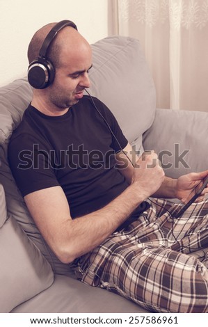 Man in pajamas sitting in the sofa and listening to the music