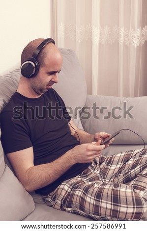 Man in pajamas sitting in the sofa and listening to the music