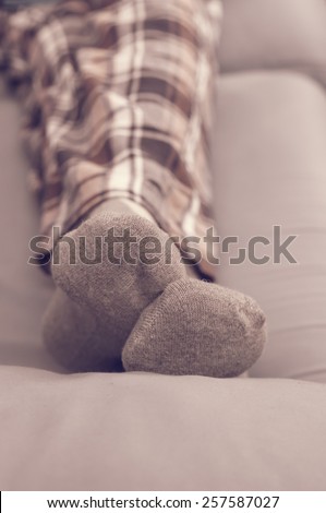 Man\'s feet resting in the sofa in pajamas