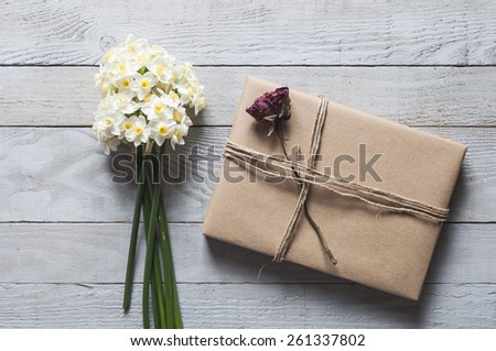 White narcissus flowers and present on wooden background