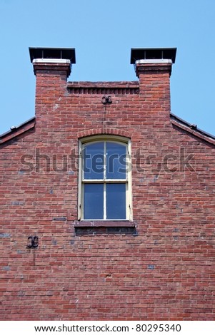 Detail of the side of the house, second floor window with chimneys.