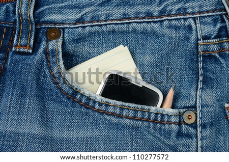 Blue jeans with paper, mobile phone and pencil in the pocket.