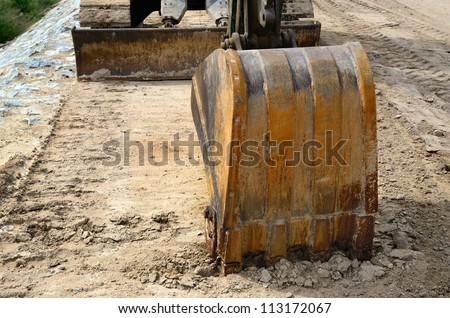 Bucket of backhoe on earth at building site.