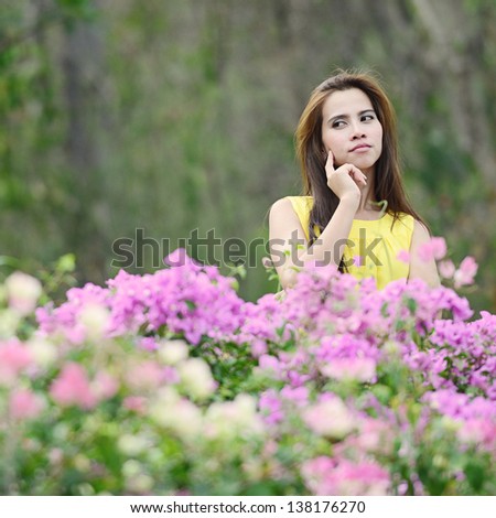 Beautiful Asian woman thinking and standing behind flower in garden.