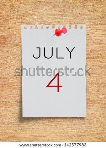 Calendar July 4 on white torn paper note with red pushpin on plywood board