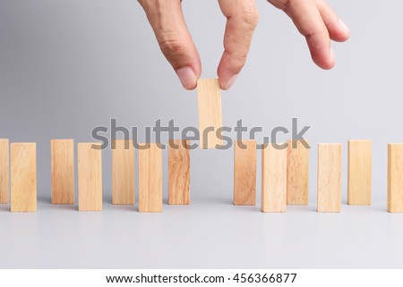 Man hand pick one of wood block from many wood block in row, metaphor to business concept in choose ideal person from many candidate. Gray background, side view.