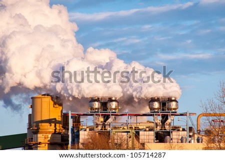 A A sugar mill factory creating smoke in front of a blue sky