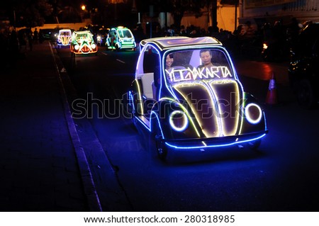 YOGYAKARTA, INDONESIA - JUNE 25, 2014: Undefined residents and tourists having fun riding on the illuminated pedal toy cars at night in Yogyakarta, Indonesia on June 25, 2014