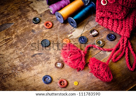 Set of spools of threads  vintage buttons with knitted cap  on old wooden table