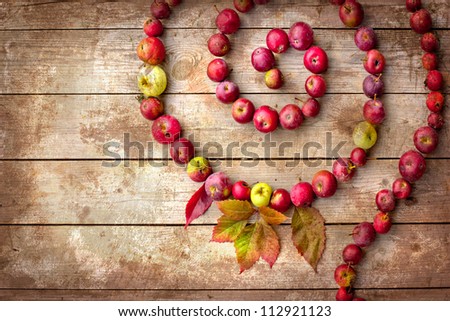 Autumn border from apples and fallen leaves on old wooden table with grunge texture/Thanksgiving day concept/background with apples
