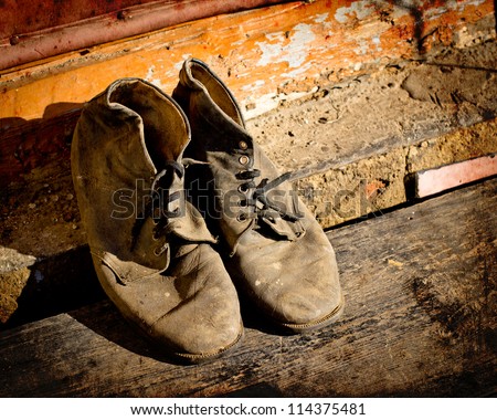 old dirty  boots.old boots worn with scratches and untied shoelaces on grunge background