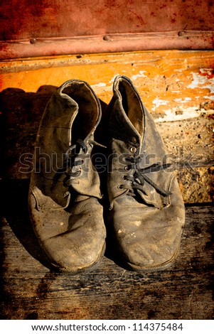 old dirty  boots.old boots worn with scratches and untied shoelaces on grunge background