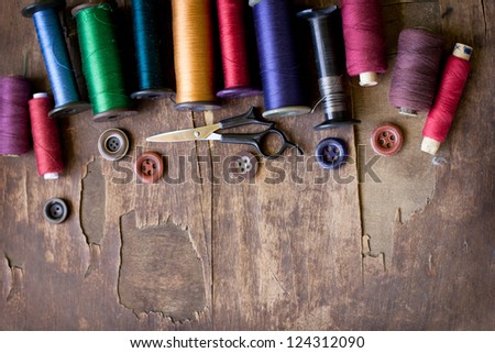 Spools of threads and buttons on old wooden table/Old sewing accessories