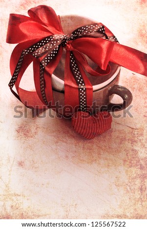 Present cup with a red  ribbon bow with heart for Valentine\'s day/vintage valentine background
