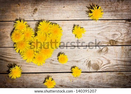 Summer background with  yellow dandelions /Heart from dandelions on a aged wooden background/Dandelions on wood with copy space