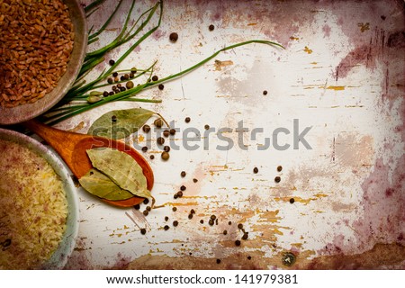 Vintage background with bowls of rice and spices,fresh herbs,with  green spring onions,bay leafs