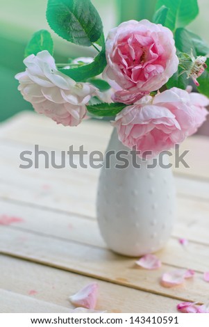 Vintage background with Pink flowers in a vase/ pink roses on light wooden table