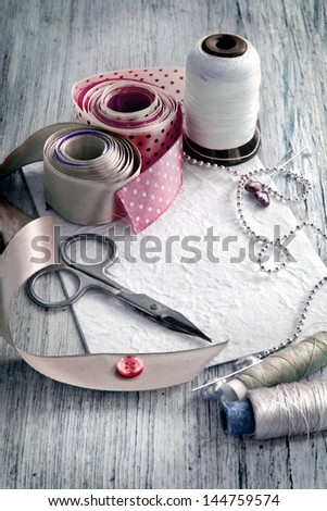 Scrapbooking craft materials/Background with sewing tools and colored tape/Sewing kit. Scissors, bobbins with thread and needles on the old wooden background