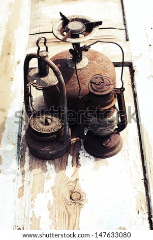 rusty old oil lamps/Three kerosene lamps on old table with grunge texture