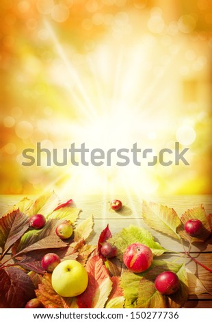 Colorful background of fallen autumn leaves and appeles on wooden table with sunbims/ Autumn border from apples and fallen leaves on old wooden table/Thanksgiving day concept/