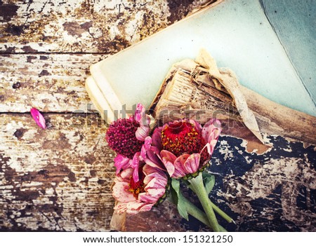 picture of a flowers lying on an antique book/ Flowers on vintage wood background with blank/romantic vintage background with dry rose and blank page