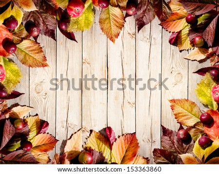 Autumn border from apples and fallen leaves on old wooden table/Thanksgiving day concept/background with apples