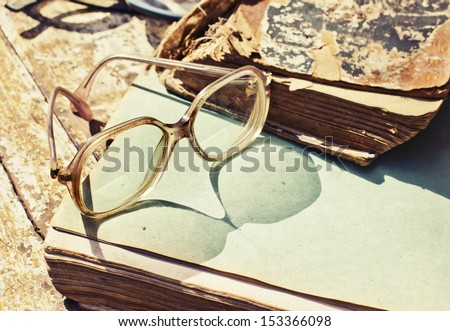 Close-up of opened book pages and glasses against vintage background/Vintage books with reading glasses in an used bookstore