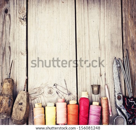 Vintage Background With Sewing Tools And Colored Tape/Sewing Kit. Scissors, Bobbins With Thread And Needles On The Old Wooden Background