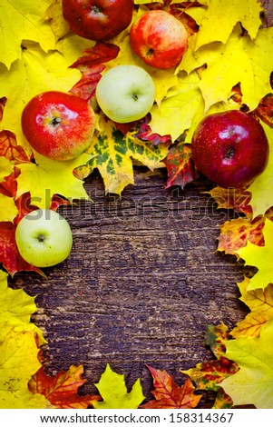 Autumn border from apples and fallen leaves on old wooden table. Thanksgiving day concept