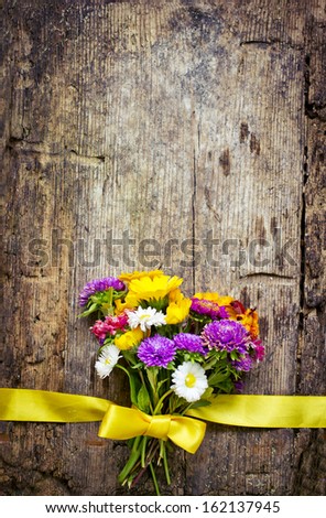 Bouquet of colorful flowers with a ribbon on wooden background/ holidays background with a flowers