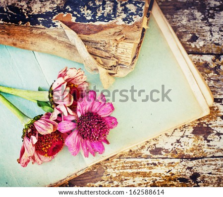 picture of a flowers lying on an antique book/Flowers on vintage wood background with blank/romantic vintage background with dry rose and blank page