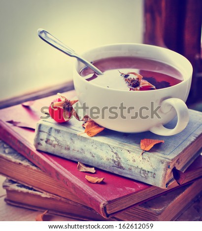 Rosehip Tea On Old Books/Tea Home With Books/Romantic Autumn Vintage Background With Books And Tea/Cup Of Tea With Hip Roses On Wooden Table