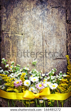 Beautiful Field white and yellow flowers with the ribbon on wooden background/ spring rustic background with flowers