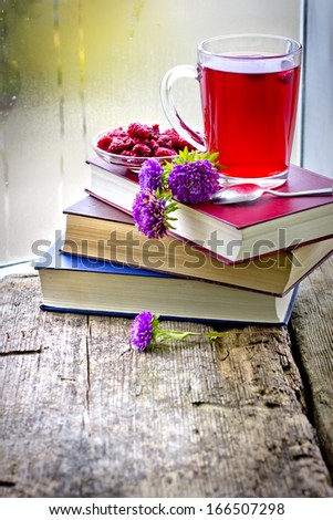 Raspberry jam tea/Romantic Autumn background with raspberry hot drink ( fruit tea) , flowers and books.