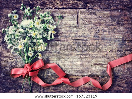 Beautiful Field white flowers with the ribbon on wooden background/ spring rustic background with flowers