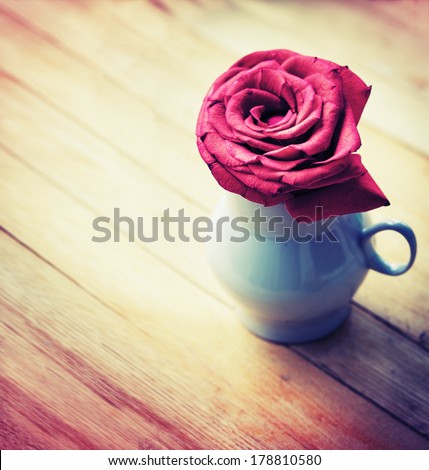 Beautiful red rose in vase on wooden desk in vintage color/ Romantic background with red rose
