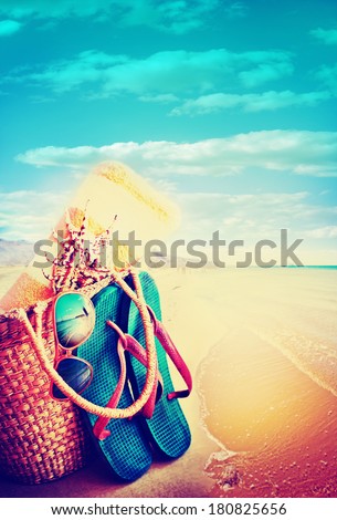Summer holidays bag, sun glasses and flip flops on a tropical beach