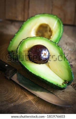Ripe avocado cut in half on a wooden table/ Fresh avocado on cutting board over wooden background