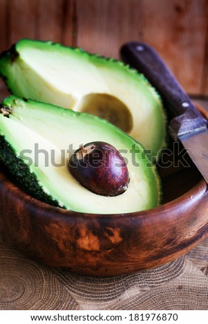Ripe avocado cut in half on a wooden table/ Fresh avocado on cutting board over wooden background