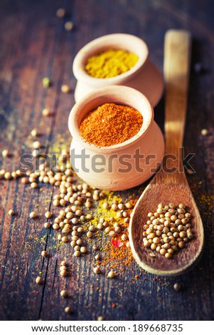 Colorful spices in bowls spilling onto an old aged scored wooden surface in a country rustic kitchen