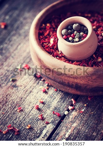 Colorful spices in bowls spilling onto an old aged scored wooden surface in a country rustic kitchen