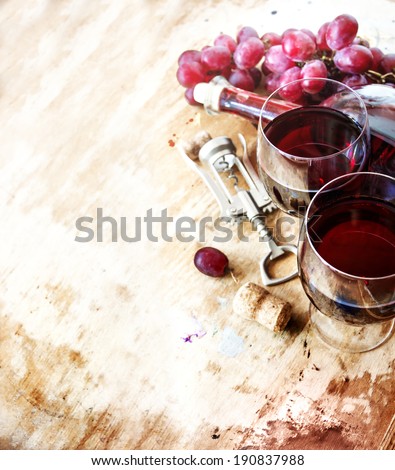 Bottle of red wine, grape and corks on wooden table