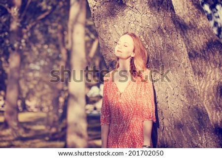 Beauty Romantic Girl Outdoors dressed in casual dress in park with sun beams. Toned in warm colors