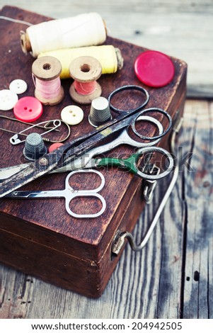 Vintage Background with sewing/Sewing kit. Scissors, bobbins with thread and needles on the old wooden background