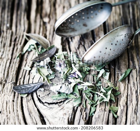 Spoon of dried green herbal tea leaves on wooden background