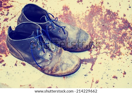 old dirty boots.old boots worn with scratches and untied shoelaces on grunge background