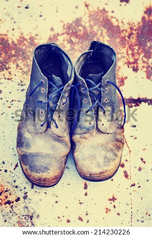 old dirty boots.old boots worn with scratches and untied shoelaces on grunge background