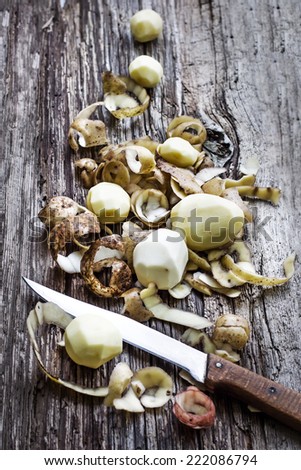 peeling potatoes.Peeling a potato with peeler in a kitchen on wooden rustic table
