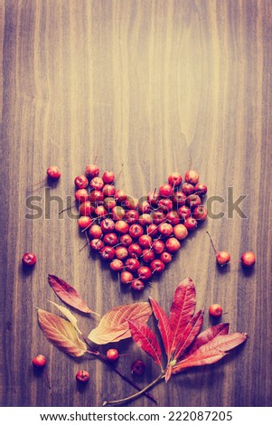 Autumn background/Autumn leaves and berry as a heart over wooden background/Thanksgiving day concept